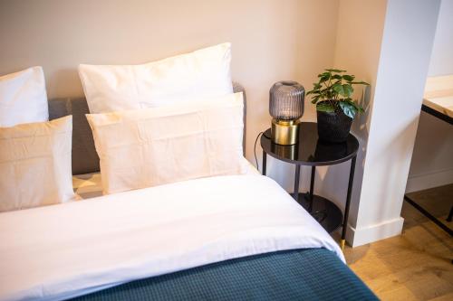 a bed with white sheets and a table with a plant at Villapark in Rotterdam