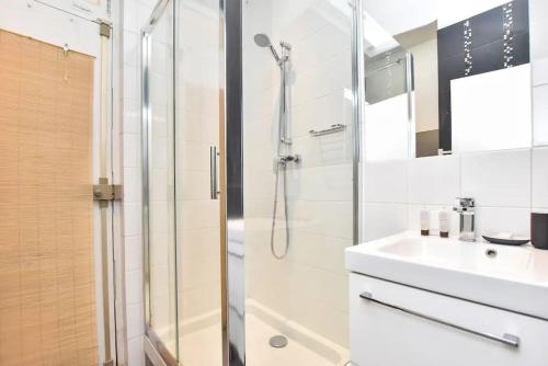 une salle de bain blanche avec une douche et un lavabo dans l'établissement GoodGuest-Appartement Design et Cosy Batignolles, à Paris