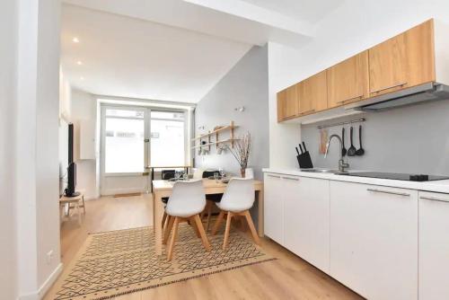 une cuisine avec des armoires blanches et une table et des chaises dans l'établissement GoodGuest-Appartement Design et Cosy Batignolles, à Paris