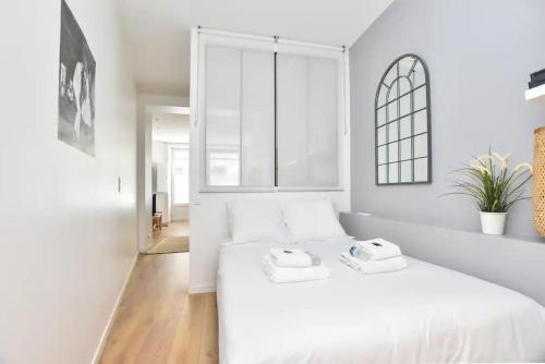 une chambre blanche avec un lit blanc et une fenêtre dans l'établissement GoodGuest-Appartement Design et Cosy Batignolles, à Paris