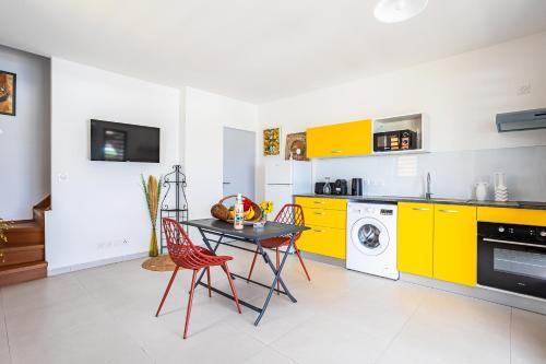 a kitchen with yellow cabinets and a table and chairs at Gîte Dalina in Saint-François