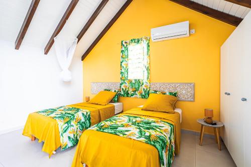 two beds in a room with yellow walls at Gîte Dalina in Saint-François