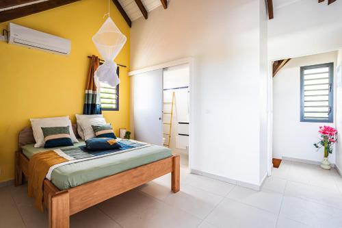 a bedroom with a bed and a yellow wall at Gîte Dalina in Saint-François
