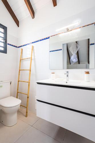 a white bathroom with a toilet and a sink at Gîte Dalina in Saint-François