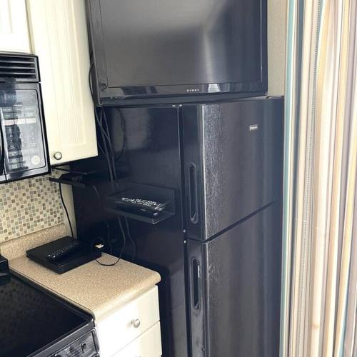 a black refrigerator in a kitchen with a microwave at A Wave From It All in Myrtle Beach