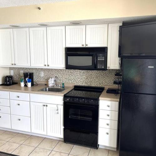 a kitchen with a black refrigerator and a sink at A Wave From It All in Myrtle Beach
