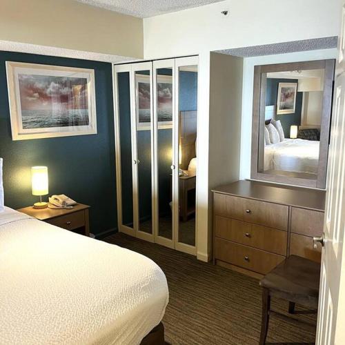 a bedroom with a bed and a dresser with a mirror at A Wave From It All in Myrtle Beach