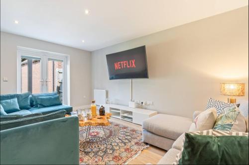 a living room with a couch and a tv on the wall at Luxury 5 bed house with Hot Tub nr Bicester Village in Bicester