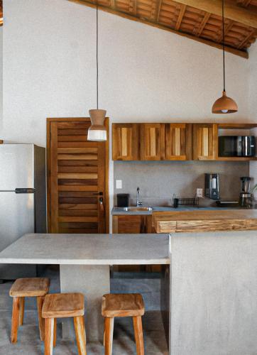a kitchen with a table and two stools at Teça Suites in Guriú