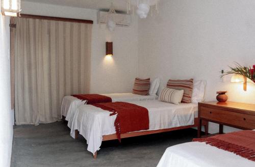 a bedroom with two beds with red and white sheets at Teça Suites in Guriú