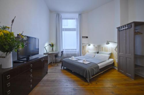 une chambre avec un lit et une télévision à écran plat dans l'établissement Courtyard Apartment (LIALI), à Berlin