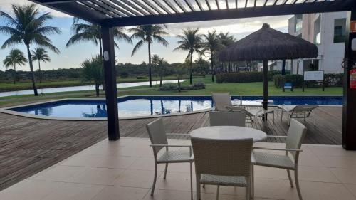 a patio with a table and chairs and a swimming pool at Praia do Forte Iberostar in Praia do Forte