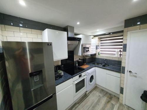 a kitchen with white cabinets and a stainless steel refrigerator at Crash pad in Luton Town in Luton