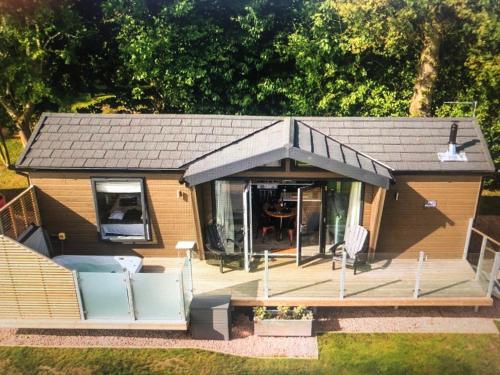 a small house with a porch and a deck at The Heather Lodge in Leven-Fife