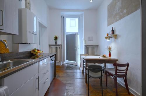 une cuisine avec des armoires blanches et une table avec des chaises dans l'établissement Courtyard Apartment (LIALI), à Berlin