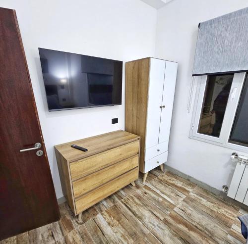 a room with a tv and a wooden dresser with a dresser at Las Victorias Suites Bariloche in San Carlos de Bariloche