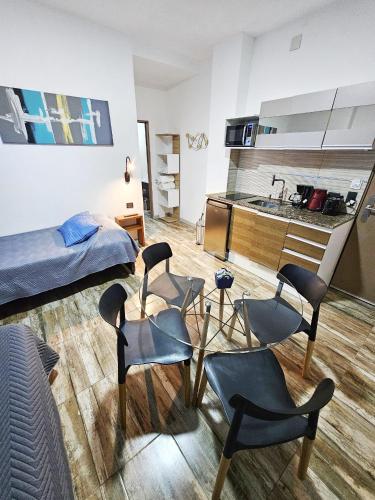 a room with chairs and a kitchen and a bed at Las Victorias Suites Bariloche in San Carlos de Bariloche