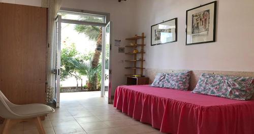 a bedroom with a bed with a red blanket and a chair at Odegos Residence Torre dell'Orso in Torre dell'Orso