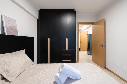 a bedroom with a white bed with a black wall at Localização Central! A 450 metros da Vila Germânica Loft com Piscina, Ar-Condicionado, Wi-Fi, Cozinha completa, Garagem Privativa, Espaço Zen, Academia, Sauna, e Mercadinho 24h in Blumenau