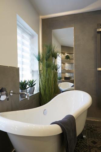 a white bath tub in a bathroom with plants at Niederhut-Residenz in Bad Neuenahr-Ahrweiler