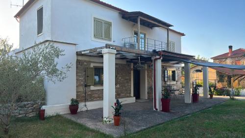 a white house with a pergola in the yard at La Villa De Rosses- Sana Halkidiki in Saná