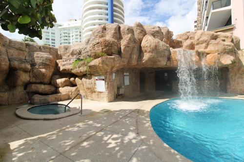 a swimming pool with a waterfall in front of a rock wall at Castle 835 Oceanview studio on beach with pool, gym, bars, and FREE Parking in Miami Beach