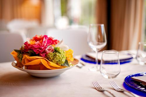 a bowl of flowers on a table with a wine glass at Locanda Al Santuario in Peschiera del Garda