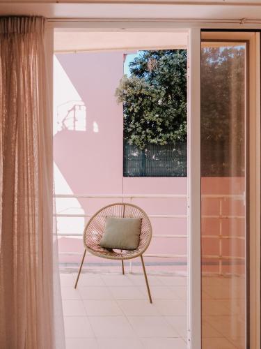 a rattan chair sitting on a porch with a window at Apartamento Sacadura Cabral - a 2 min da praia in Vila do Conde