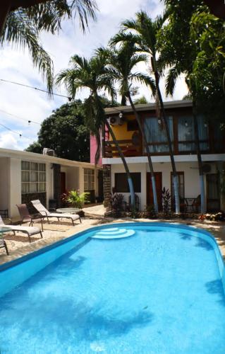 a pool in front of a house with palm trees at Coconut Beach House in Playa Conchal