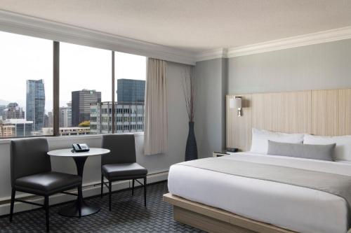 a hotel room with a bed and a table and chairs at Century Plaza Hotel in Vancouver