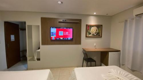 a hotel room with a bed and a tv on the wall at Hotel Nova Aliança in Chapadão do Sul
