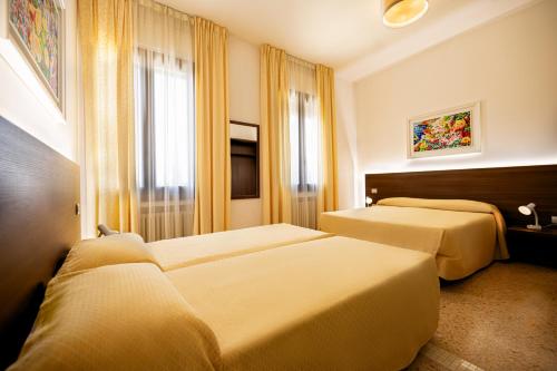 a hotel room with three beds and a window at Locanda Al Santuario in Peschiera del Garda