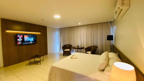 a hotel room with a bed and a tv on the wall at Hotel Nova Aliança in Chapadão do Sul