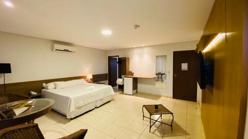 a hotel room with a bed and a table at Hotel Nova Aliança in Chapadão do Sul