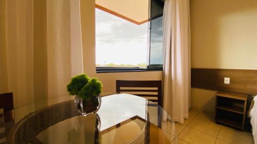 a dining room with a glass table and a window at Hotel Nova Aliança in Chapadão do Sul