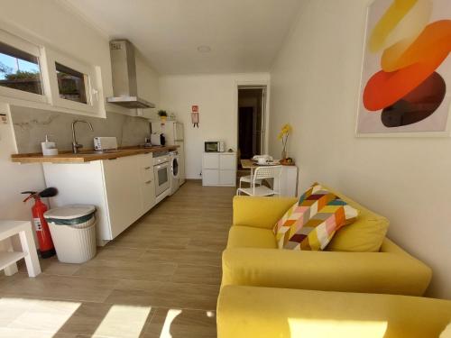 a living room with a yellow couch and a kitchen at Caparica Studio - Sclusive Stay in Costa da Caparica