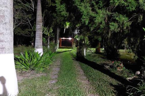 a path in a park at night with trees at Sítio Gramado Sarapuí, lazer, conforto e diversão in Alambari
