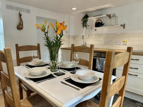 a dining room table with chairs and a vase with flowers at Wothorpe House, 3 bed Stamford Centre by Belmont Places in Lincolnshire