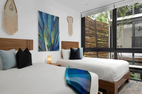two beds in a room with a window at Private Rooftop Pool - Bike to Ruins or Beach in Tulum