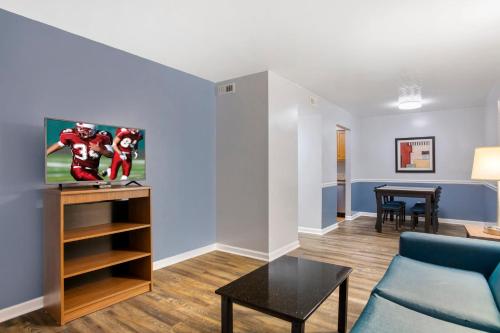 a living room with a couch and a tv at HomeTowne Studios by Red Roof Huntsville - Madison in Madison