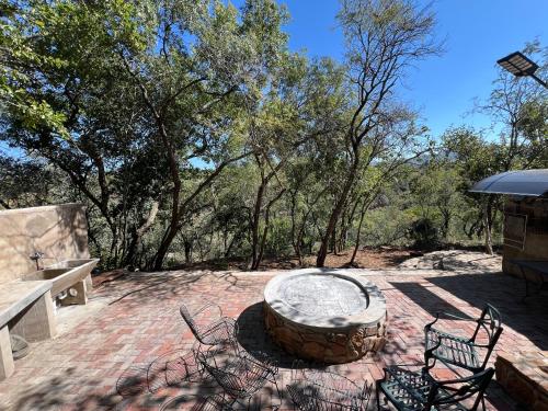 a patio with a fire pit and chairs and trees at Nectar Game Lodge in Buffelspoort