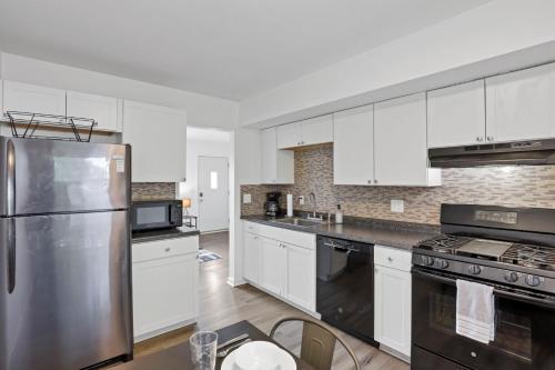 a kitchen with white cabinets and a stainless steel refrigerator at The Northtowne Getaway in Columbus