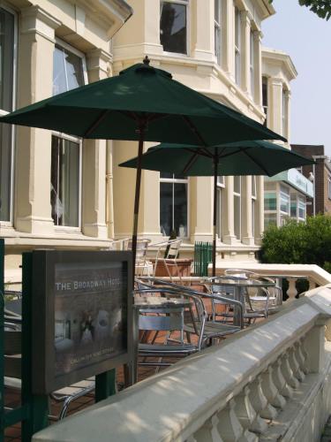 a patio with tables and chairs with an umbrella at The Broadway Hotel in Llandudno