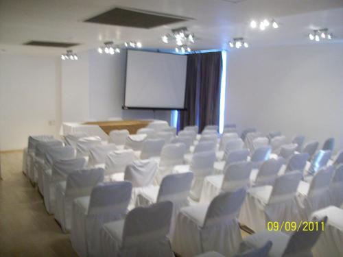 a conference room with white chairs and a screen at Hotel Inglaterra in Tampico