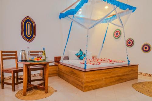 a bedroom with a canopy bed with a table and a chair at TIANDE Boutique Hotel in Pwani Mchangani