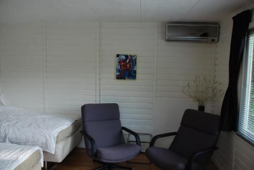een slaapkamer met 2 stoelen, een bed en een ventilator bij de Rentmeester in Amstelveen