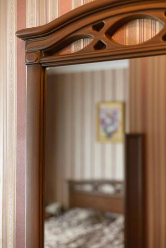 a mirror with a wooden frame in a bedroom at Hotel-Restaurant Lyube Plus in Khmelʼnytsʼkyy