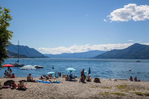 a group of people on a beach near the water at La Torretta "I Gabbiani" sul Lago Maggiore in Maccagno Inferiore