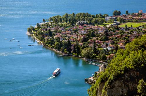 a boat is docked in a river next to a town at La Torretta "I Gabbiani" sul Lago Maggiore in Maccagno Inferiore