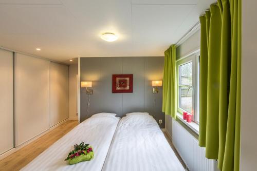 two beds in a room with green curtains at Ferienhaus 4 Personen bei Giethoorn, Chalet in Holland in De Bult